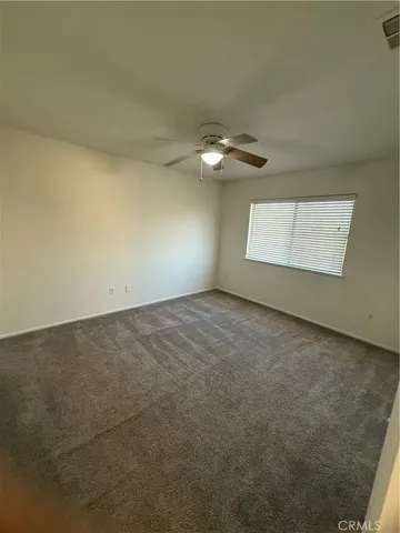 an empty room with a chandelier fan and windows