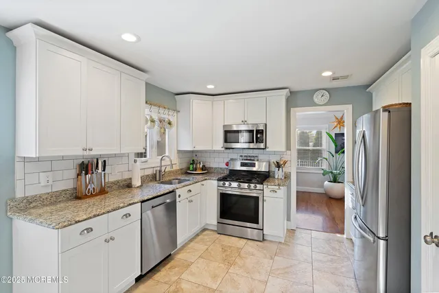 a kitchen with stainless steel appliances granite countertop a stove a sink dishwasher a refrigerator and a oven with wooden floor