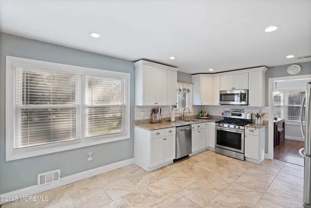 a kitchen with stainless steel appliances granite countertop a stove top oven a sink dishwasher and a refrigerator