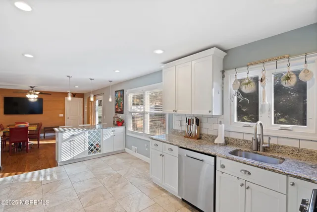a large white kitchen with a large window and stainless steel appliances