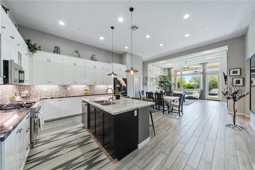 35162 Ladybug Lane Murrieta, CA 92563 - Photo 11 of 58 a kitchen with stainless steel appliances granite countertop a stove oven a refrigerator a sink and white cabinets with wooden floor next to windows
