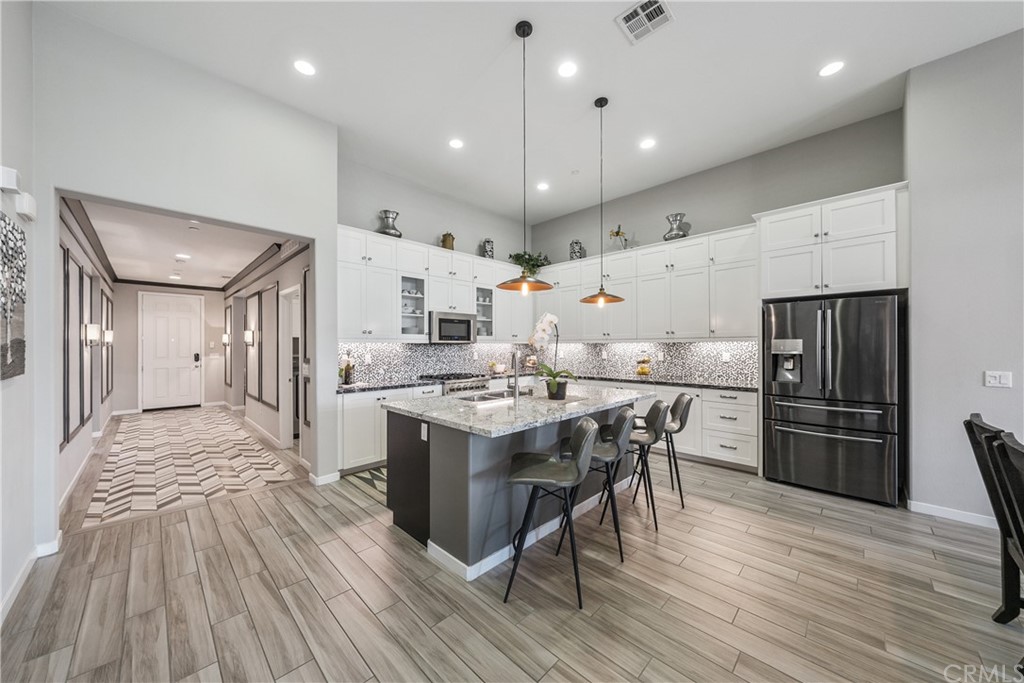 35162 Ladybug Lane Murrieta, CA 92563 - Photo 14 of 58 a large kitchen with stainless steel appliances kitchen island granite countertop a stove a refrigerator a sink a dining table and chairs with wooden floor