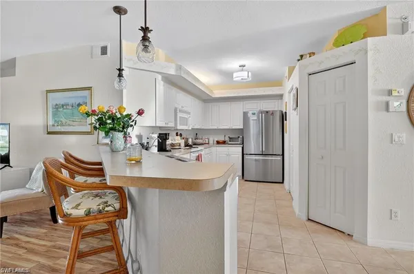 a kitchen with stainless steel appliances a sink a table chairs and refrigerator