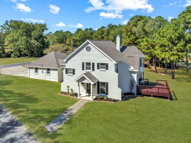 a white house with a big yard and large trees