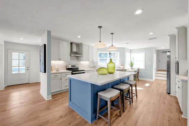 a kitchen with stainless steel appliances a dining table chairs stove refrigerator and cabinets