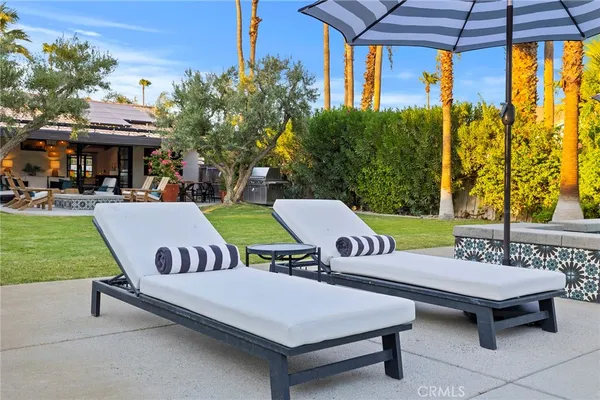 a view of a patio with table and chairs potted plants and a palm tree