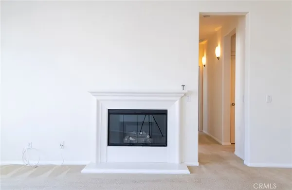 a view of an empty room with wooden floor and a fireplace