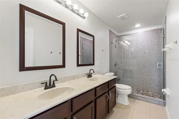 a bathroom with a double vanity sink toilet mirror and shower