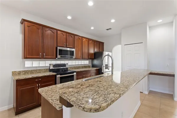 a kitchen with stainless steel appliances granite countertop a sink dishwasher stove and microwave with wooden cabinets