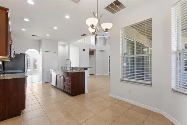 a large kitchen with kitchen island granite countertop a stove a sink a counter top space and cabinets
