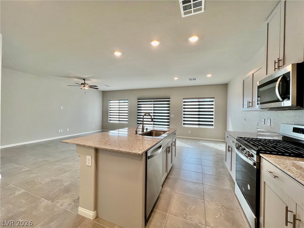 7845 Morganite Avenue Las Vegas, NV 89113 - Photo 7 of 21 An open concept kitchen features stainless steel appliances, granite countertops, and an island with a sink.