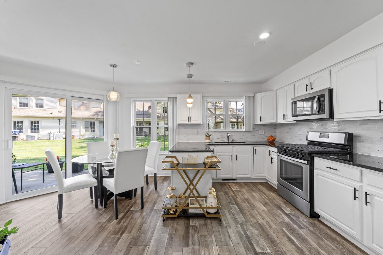 706 Brandon Place Wheeling, IL 60090 - Photo 16 of 42 a kitchen with a table chairs stove and white cabinets