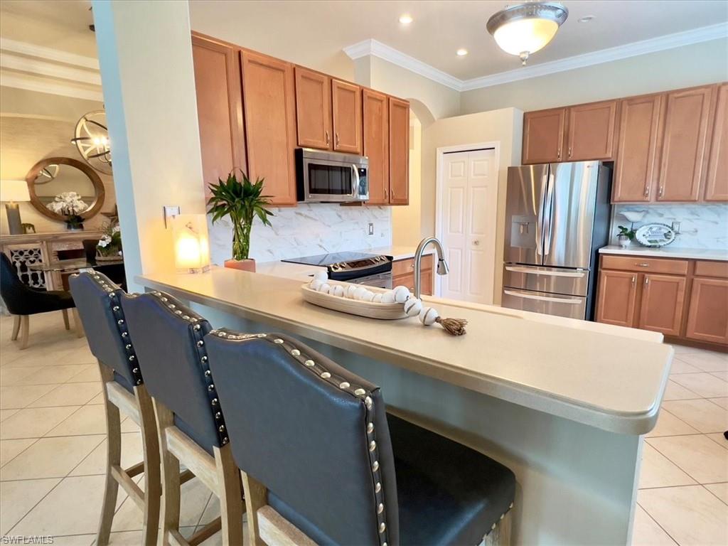 14291 Manchester Drive Naples, FL 34114 - Photo 15 of 49 a kitchen with stainless steel appliances a sink a stove a microwave a refrigerator and cabinets