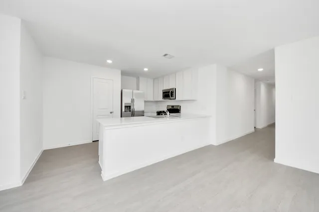 a view of kitchen with stainless steel appliances granite countertop white cabinets and refrigerator