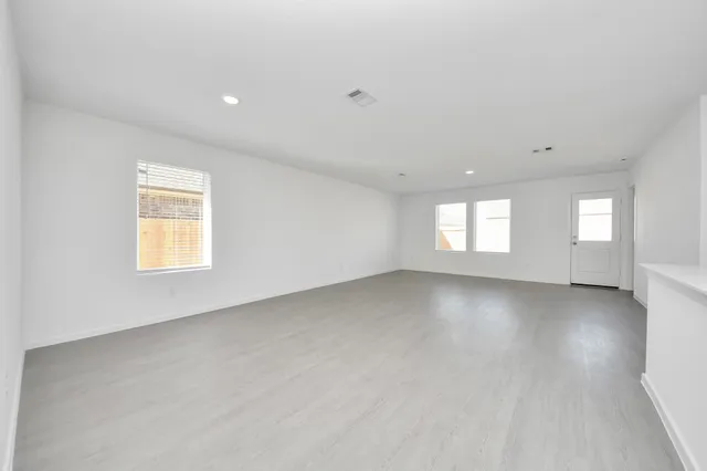 a view of an empty room with a window and a kitchen