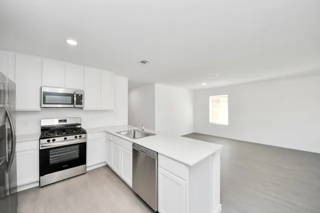 a kitchen with stainless steel appliances a stove top oven a sink a counter space and cabinets