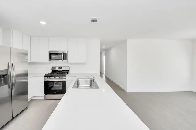a kitchen with a refrigerator a stove top oven and white cabinets