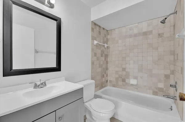 a bathroom with a bathtub shower sink vanity mirror and toilet