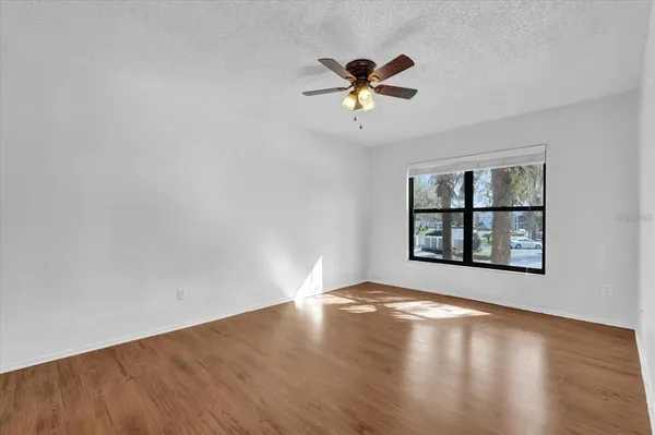 a view of empty room with wooden floor and window