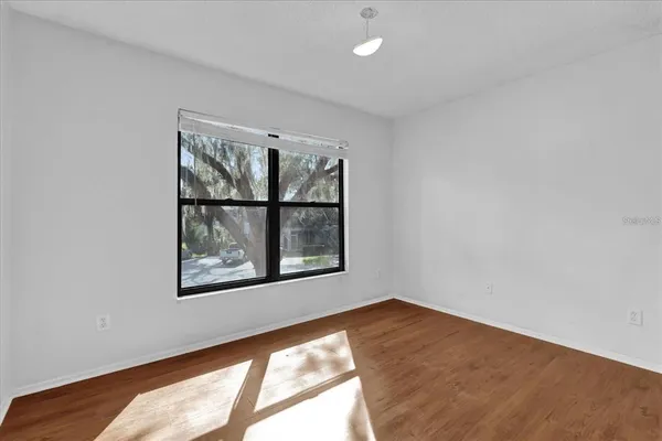 a view of an empty room with a chandelier fan and wooden floor