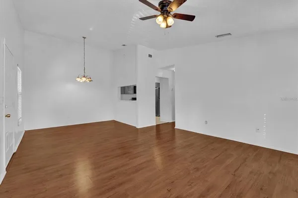 a view of an empty room with wooden floor and a chandelier