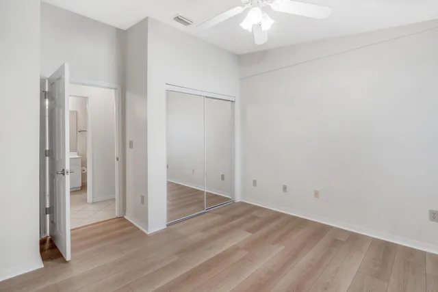 an empty room with wooden floor and a ceiling fan