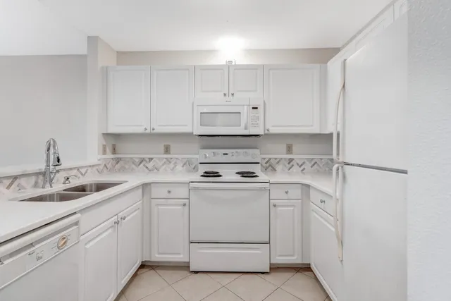 a kitchen with white cabinets appliances and sink