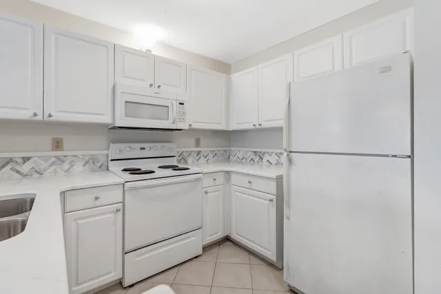 a kitchen with white cabinets and white appliances