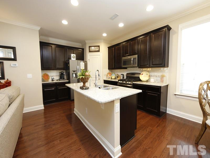 1145 Chapanoke Road Raleigh, NC 27603 - Photo 9 of 25 The kitchen has plenty of cabinets, granite counters including the large island, a subway tile backsplash and stainless appliances with a gas range.