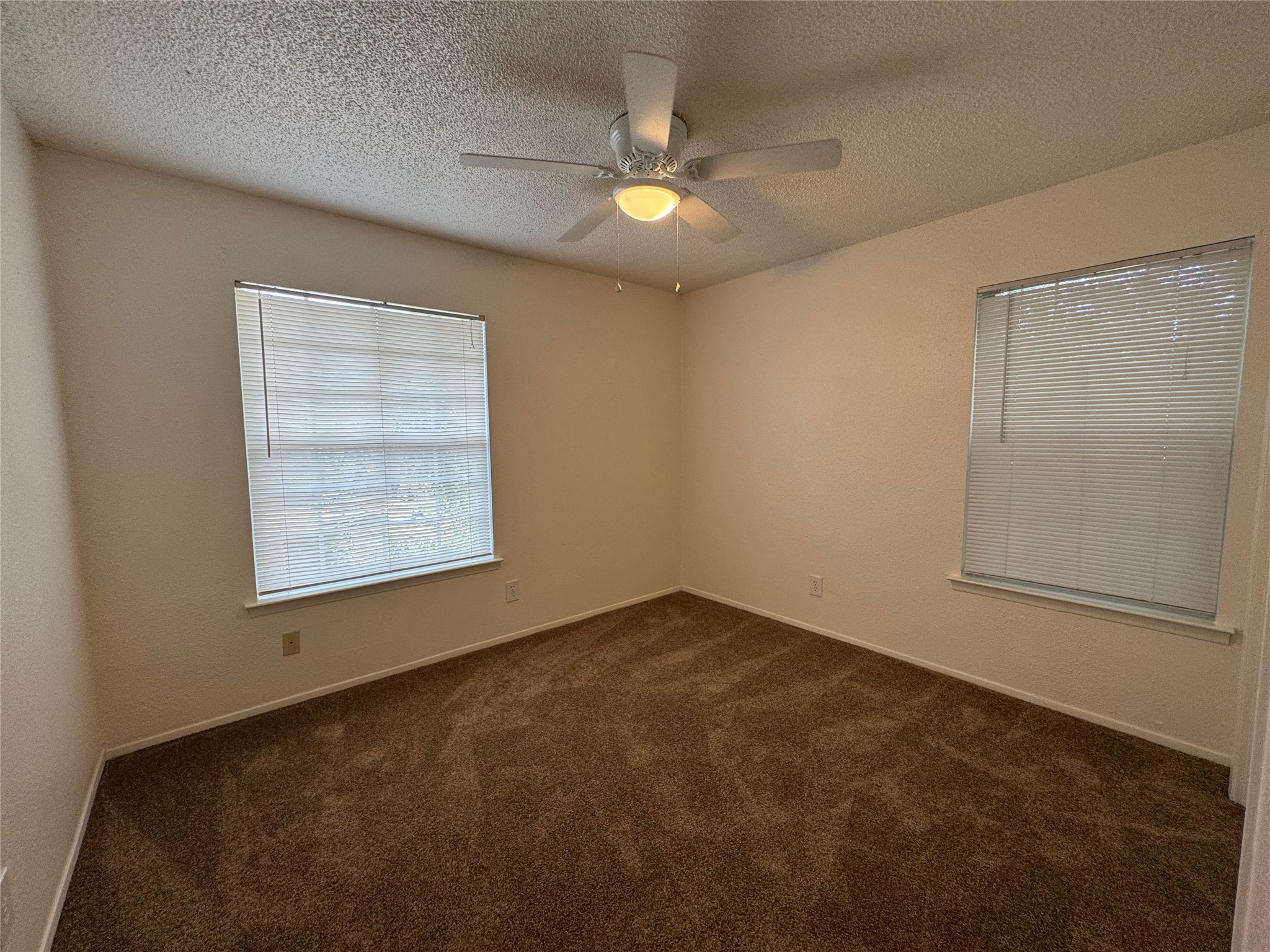 4810 West Wind Trail, Unit 102 Austin, TX 78745 - Photo 13 of 23 an empty room with a chandelier fan and windows