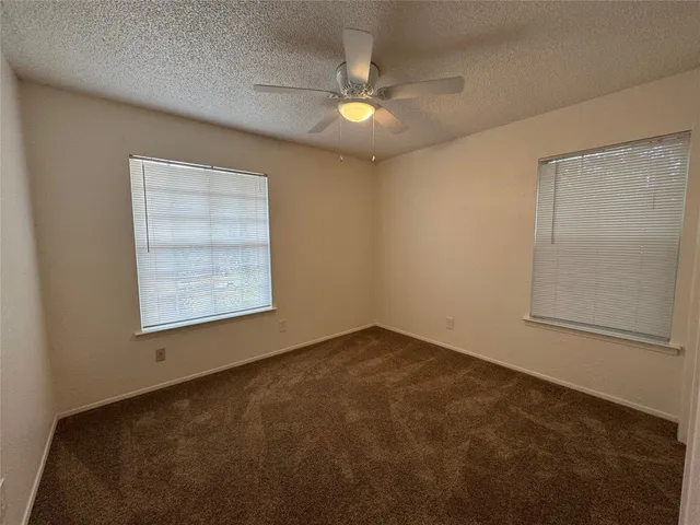 an empty room with a chandelier fan and windows