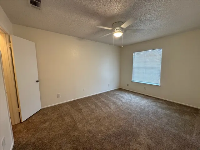 an empty room with a ceiling fan and window