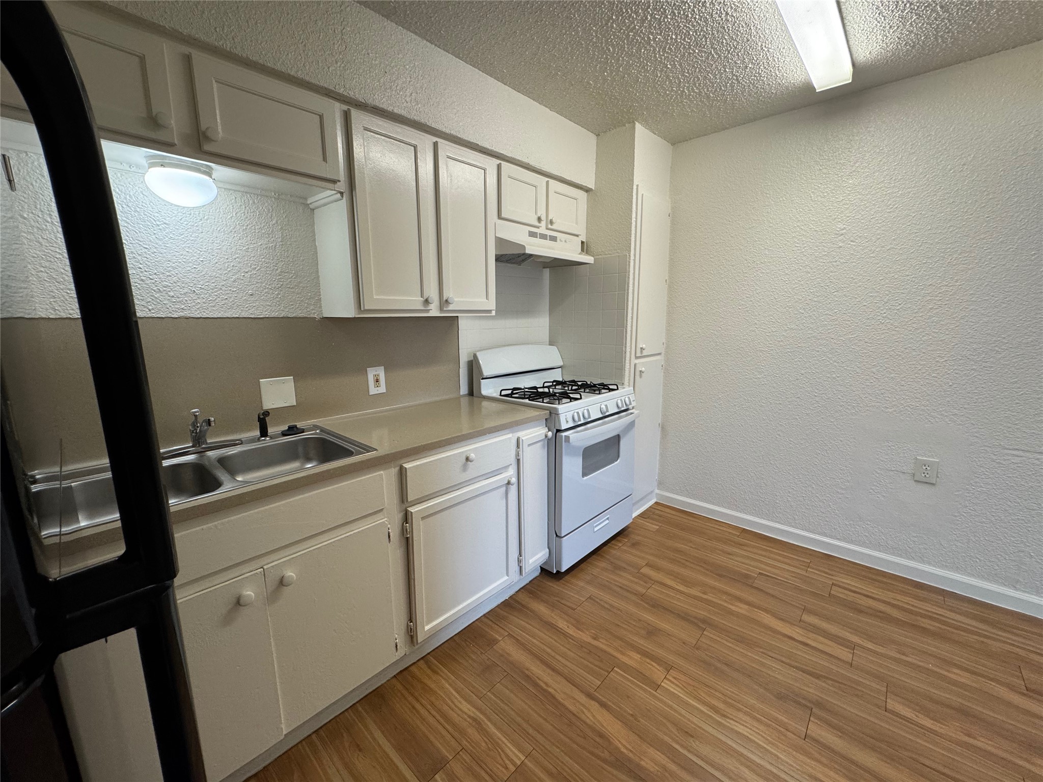 4810 West Wind Trail, Unit 102 Austin, TX 78745 - Photo 6 of 23 a kitchen with sink cabinets and wooden floor