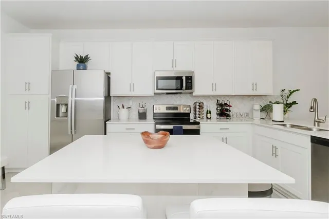 a white kitchen with a refrigerator a stove a sink and white cabinets