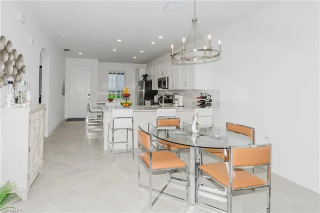 a dining room filled chandelier and kitchen view