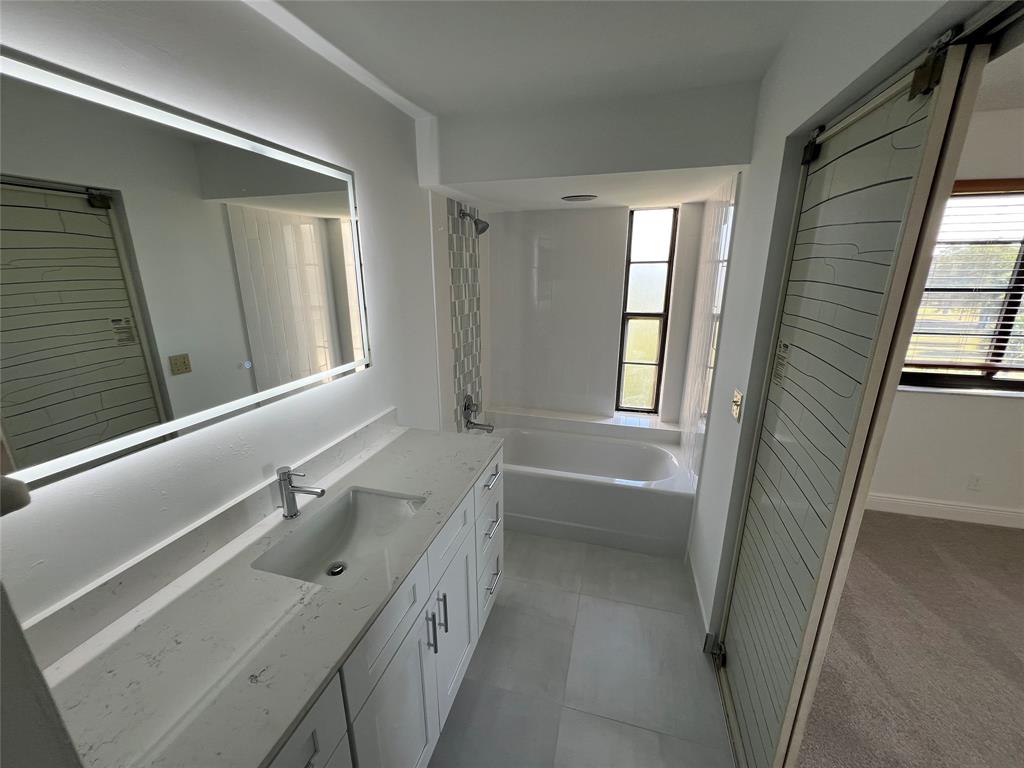 9300 Southwest 8th Street, Unit 422 Boca Raton, FL 33428 - Photo 32 of 38 a bathroom with a tub sink and mirror