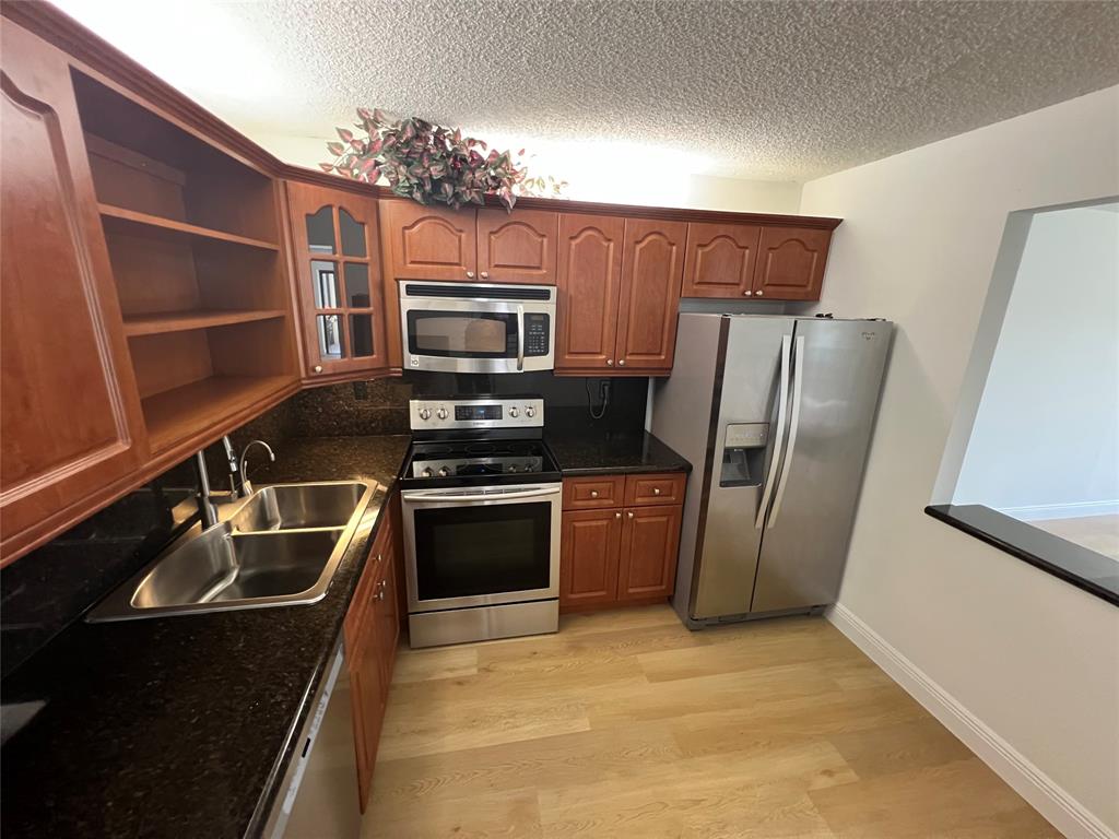 9300 Southwest 8th Street, Unit 422 Boca Raton, FL 33428 - Photo 9 of 38 a kitchen with granite countertop a refrigerator and a sink