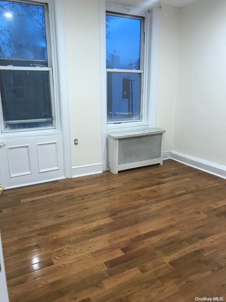 453 Ridgewood Avenue, Unit 2 Brooklyn, NY 11208 - Photo 6 of 11 Empty room featuring dark wood-style flooring and radiator heating unit