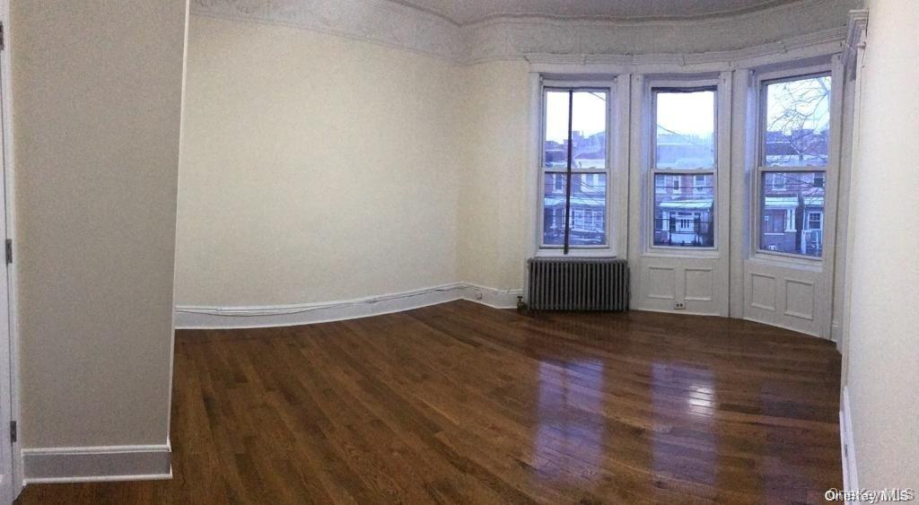 453 Ridgewood Avenue, Unit 2 Brooklyn, NY 11208 - Photo 10 of 11 Spare room with dark wood-style flooring and radiator
