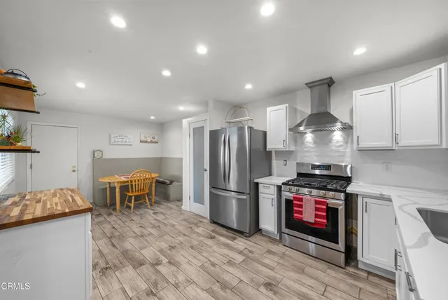 a kitchen with stainless steel appliances kitchen island granite countertop a refrigerator a stove and a sink with wooden floor