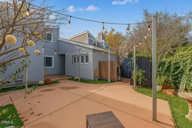 a backyard of a house with table and chairs under an umbrella
