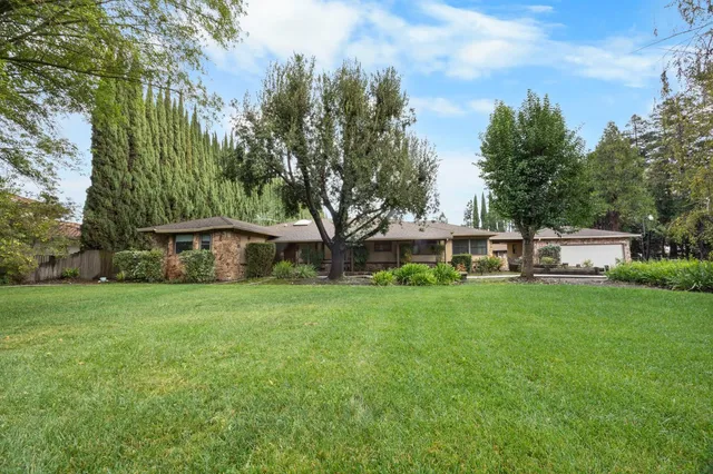 a view of a big house with a big yard and large trees