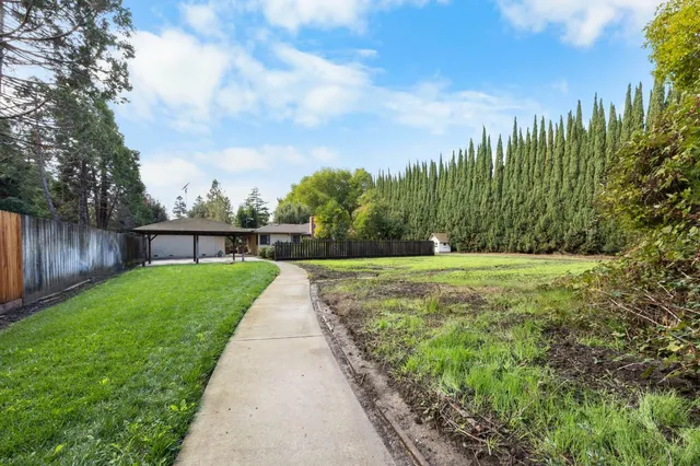 a view of an house with backyard and a tree