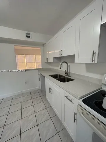 a kitchen with white cabinets a sink and white appliances