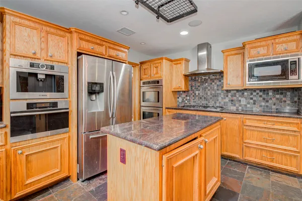 a kitchen with stainless steel appliances granite countertop a refrigerator a stove and a sink