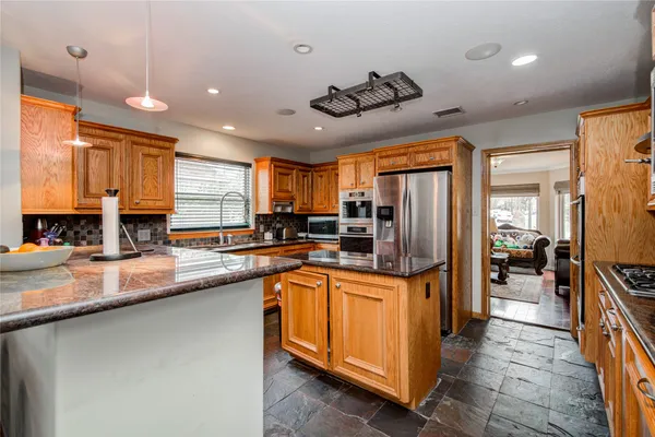 a kitchen with stainless steel appliances granite countertop a refrigerator a sink a stove and island