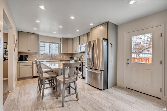 1697 North 500 West Mapleton, UT 84664 - Photo 10 of 50 Kitchen featuring stainless steel appliances, light stone countertops, a center island, a breakfast bar area, and backsplash