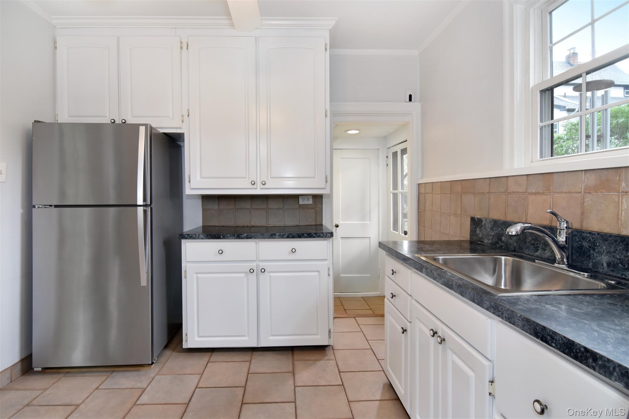 370 Scarsdale Road Tuckahoe, NY 10707 - Photo 16 of 25 Kitchen featuring white cabinetry, dark countertops, tiled backsplash, stainless steel appliances, and tile flooring