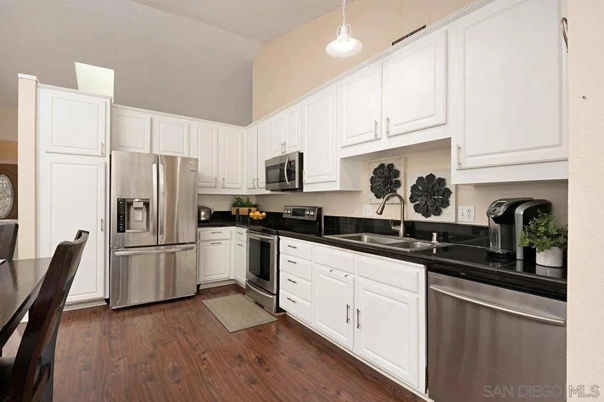 11068 Pinzon Way San Diego, CA 92127 - Photo 12 of 31 a kitchen with granite countertop a refrigerator stove a sink and dishwasher with wooden floor