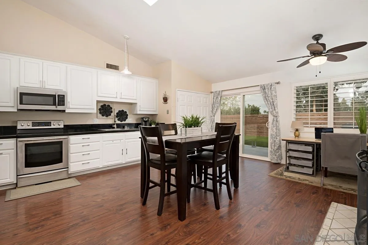 11068 Pinzon Way San Diego, CA 92127 - Photo 10 of 31 a kitchen with stainless steel appliances kitchen island granite countertop a stove a sink a dining table and chairs with wooden floor